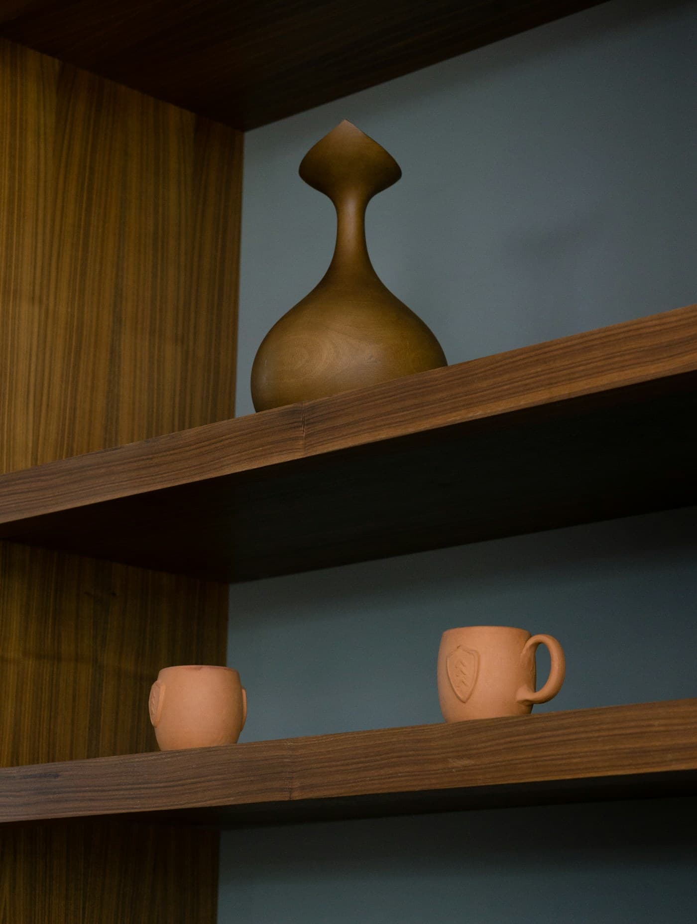Open teak shelving with terracotta and turned-wood vessels