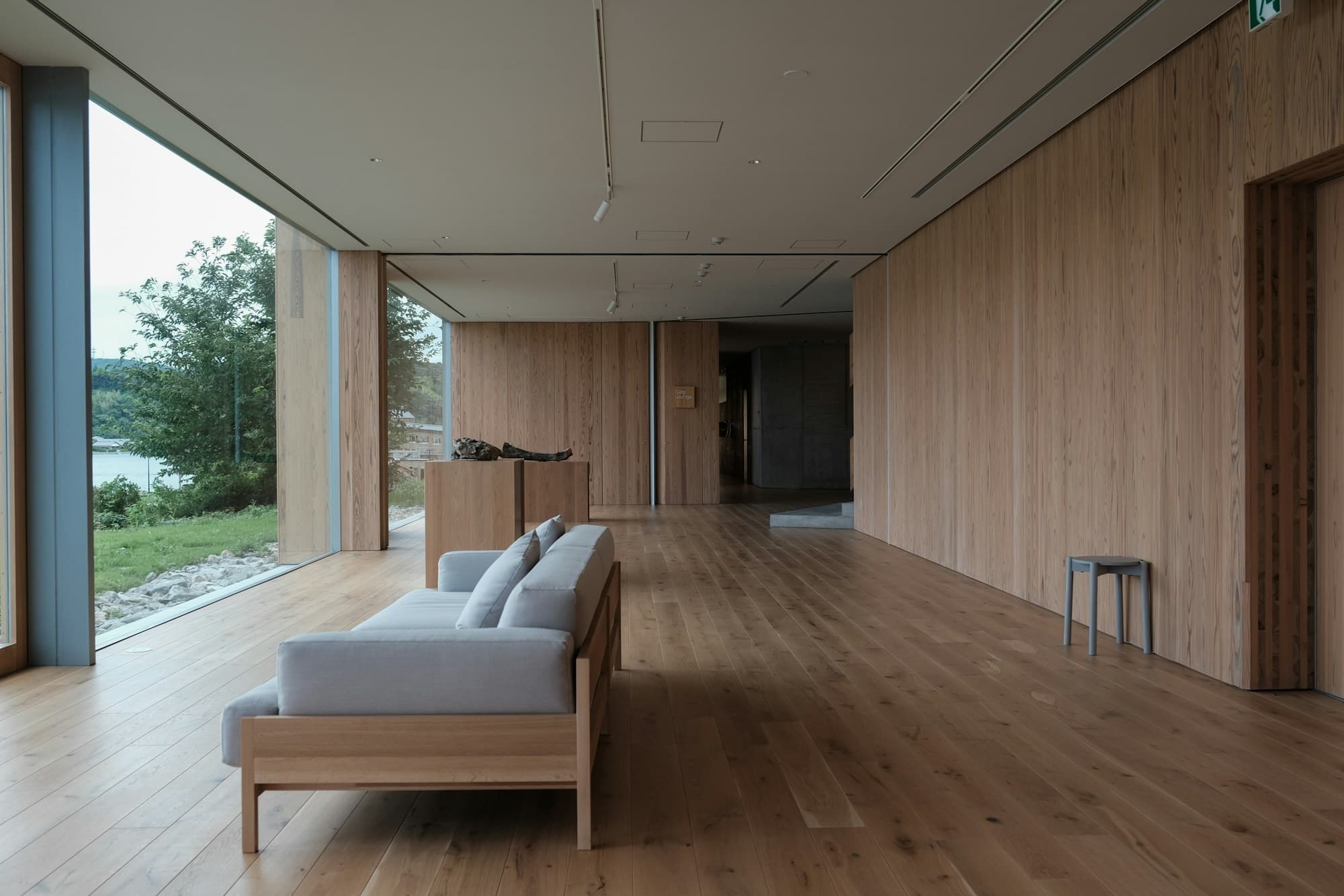 Timber-clad room with floor-to-ceiling glazing, a solid wood daybed and wide oak floor in soft daylight
